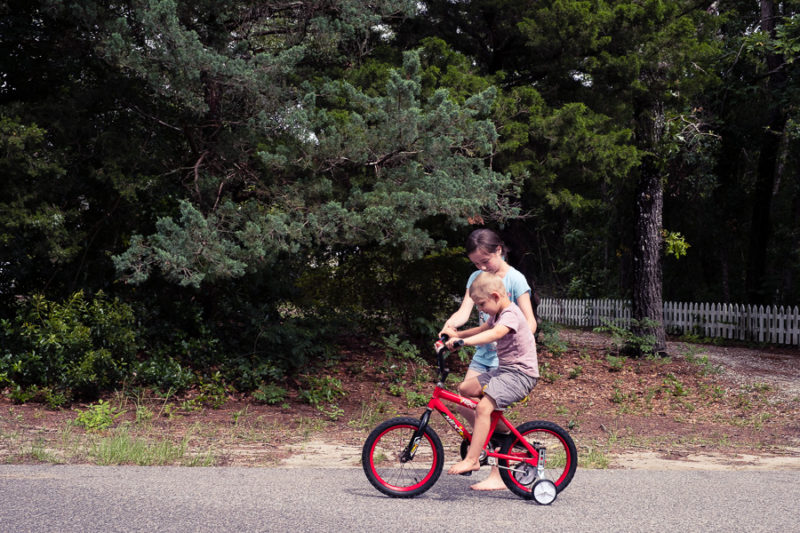 A little boy getting a bike riding lesson from his young aunt 